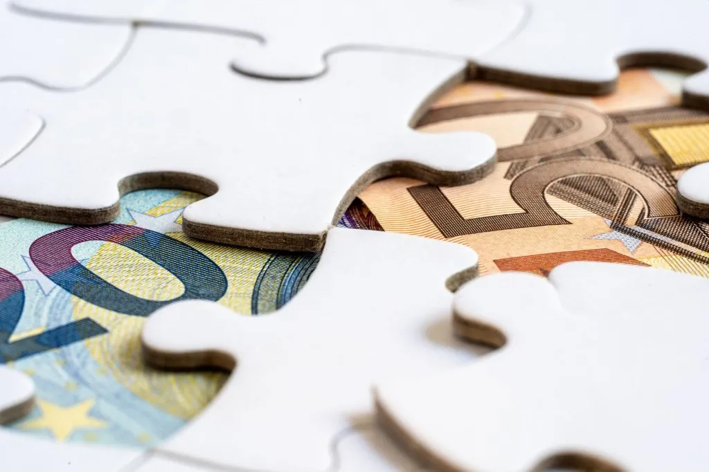 Billets euros visibles sous des pièces de puzzle symbolisant solutions financières