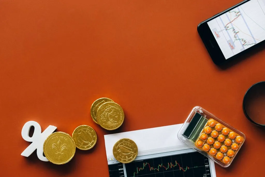 Pièces de monnaie calculatrice et graphiques sur fond rouge analyse financière