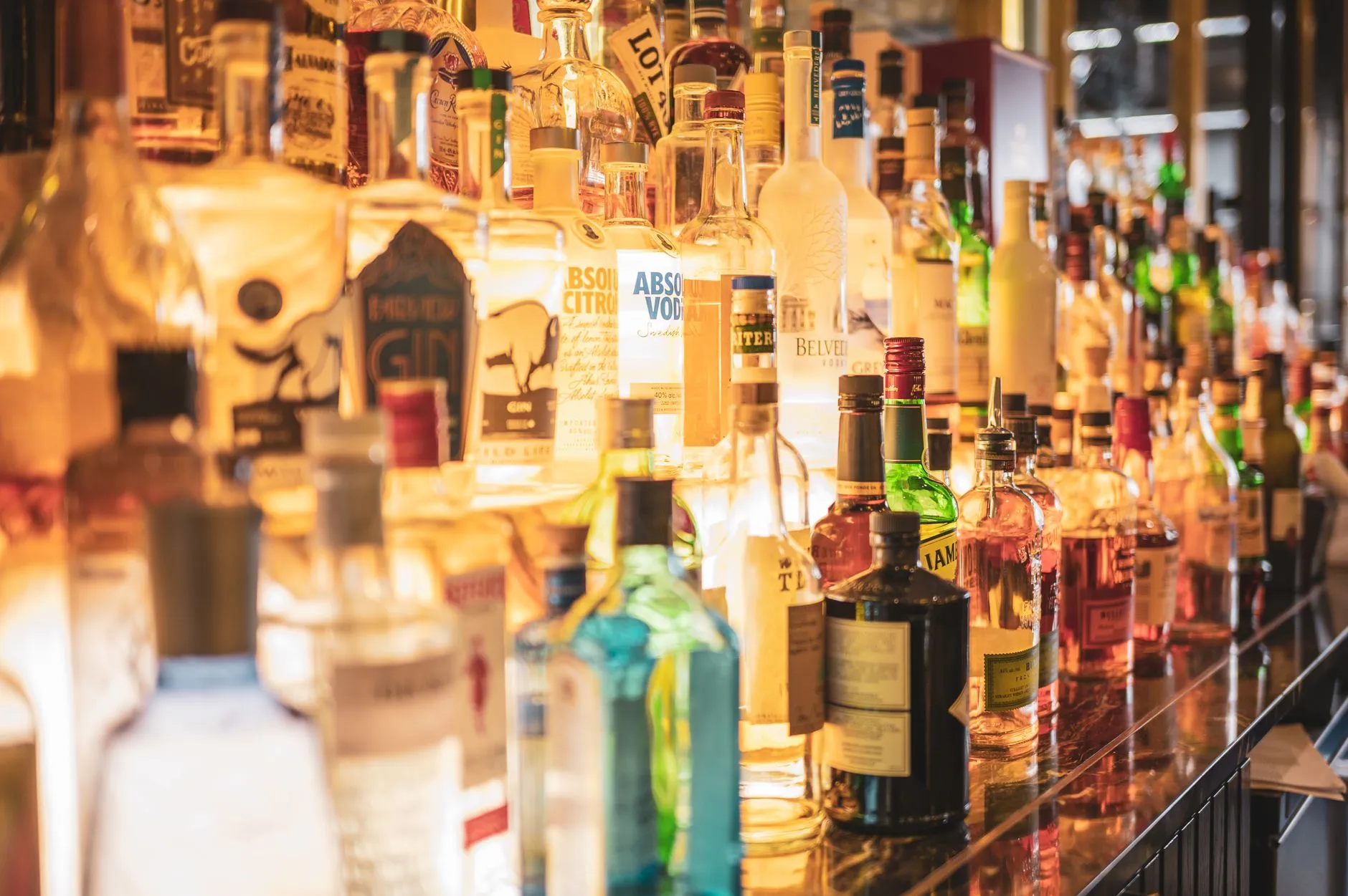 Bouteilles de spiritueux alignées sur le comptoir éclairé d'un bar