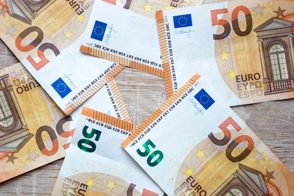 Billets de 50 euros éparpillés sur fond bois - dividendes perçus