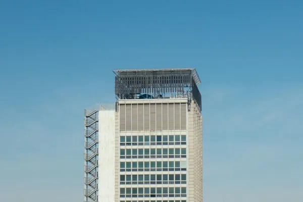 Sommet d’une tour de bureaux claire sous un ciel bleu