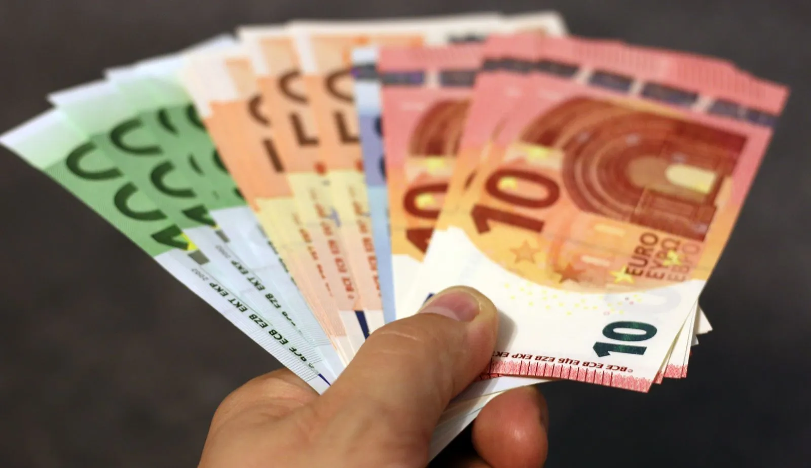 Éventail de billets en euros de différentes coupures tenus en main