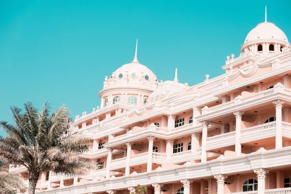 Façade d'un hôtel de luxe avec palmiers sous un ciel bleu