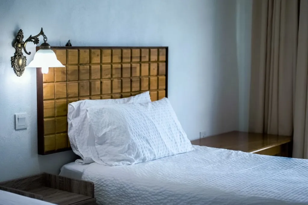 Chambre d'hôtel avec tête de lit en bois et literie blanche