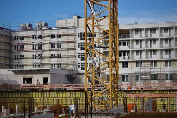 Grue jaune devant un immeuble en construction entouré d’échafaudages